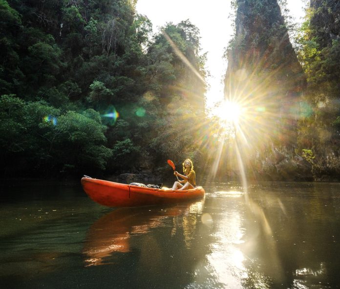Cheerful woman sea kayaking among karst formations and mangrove forest on Krabi